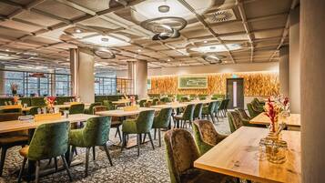A spacious dining area with multiple tables and chairs, a patterned carpet, and a modern ceiling design.