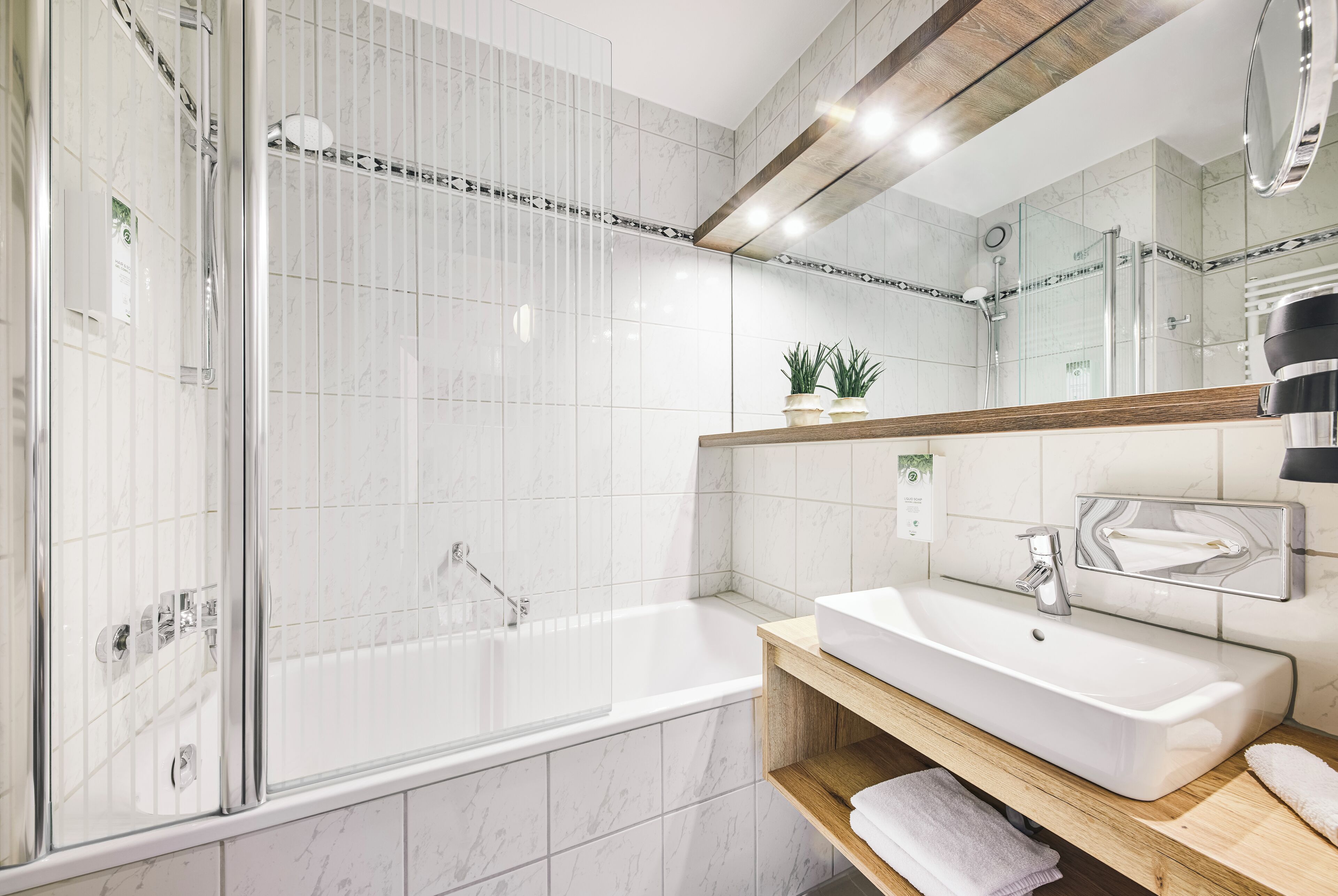 A modern bathroom with a glass-enclosed shower, a standalone bathtub, and a vanity with a mirror.