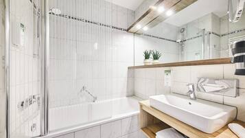 A modern bathroom with a glass-enclosed shower, a standalone bathtub, and a vanity with a mirror.