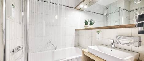 A modern bathroom with a glass-enclosed shower, a standalone bathtub, and a vanity with a mirror.