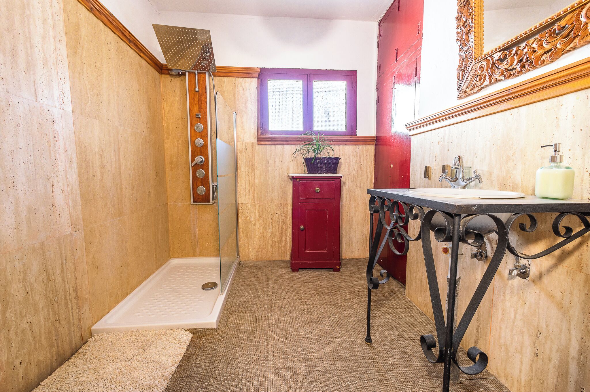 A bathroom with a shower, a sink, and a red cabinet.