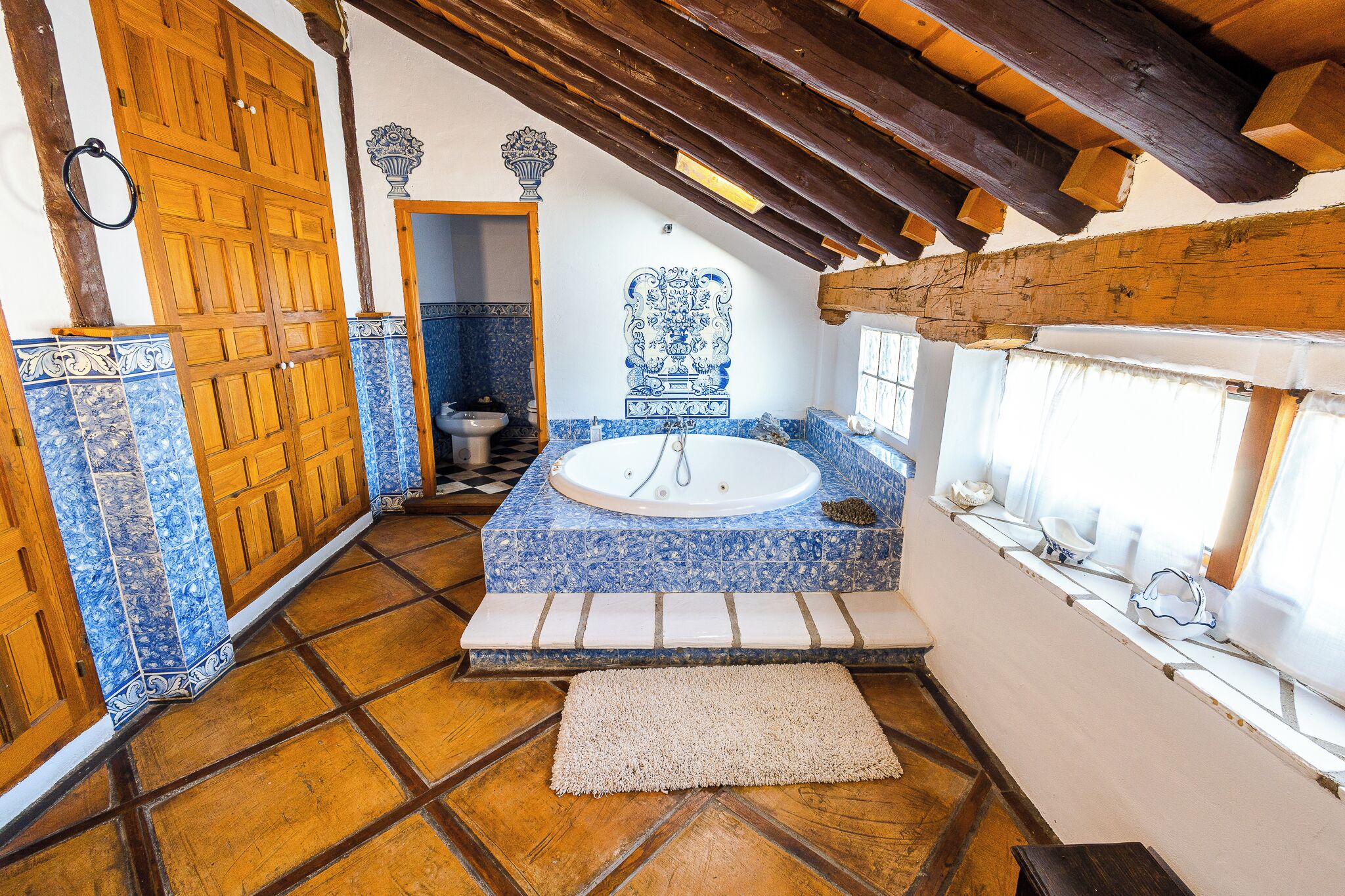 A bathroom with a bathtub, wooden door, and tiled floor.