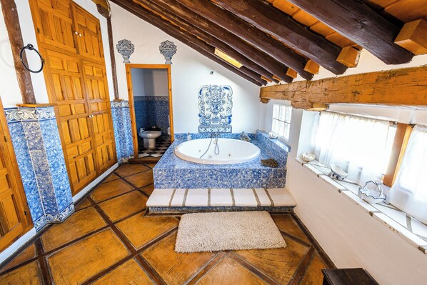 A bathroom with a bathtub, wooden door, and tiled floor.