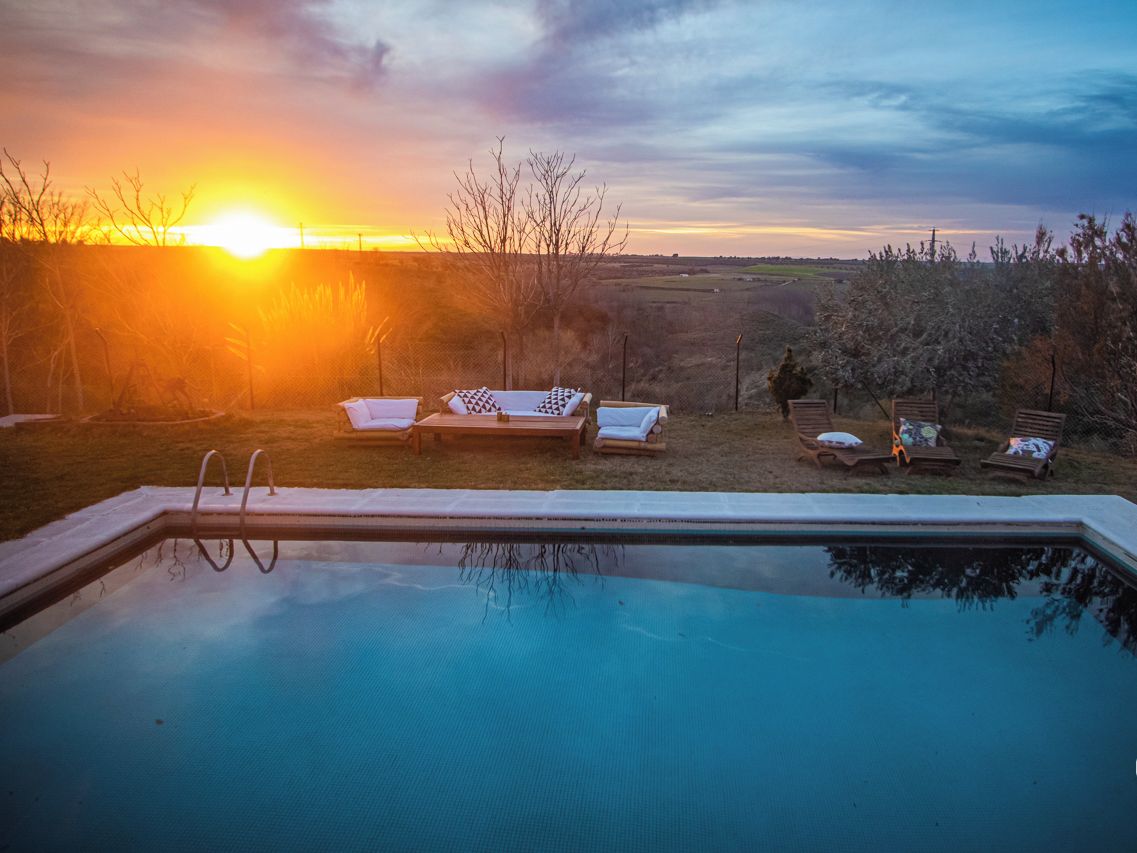 Ein Swimmingpool mit Liegestühlen und Blick auf den Sonnenuntergang.