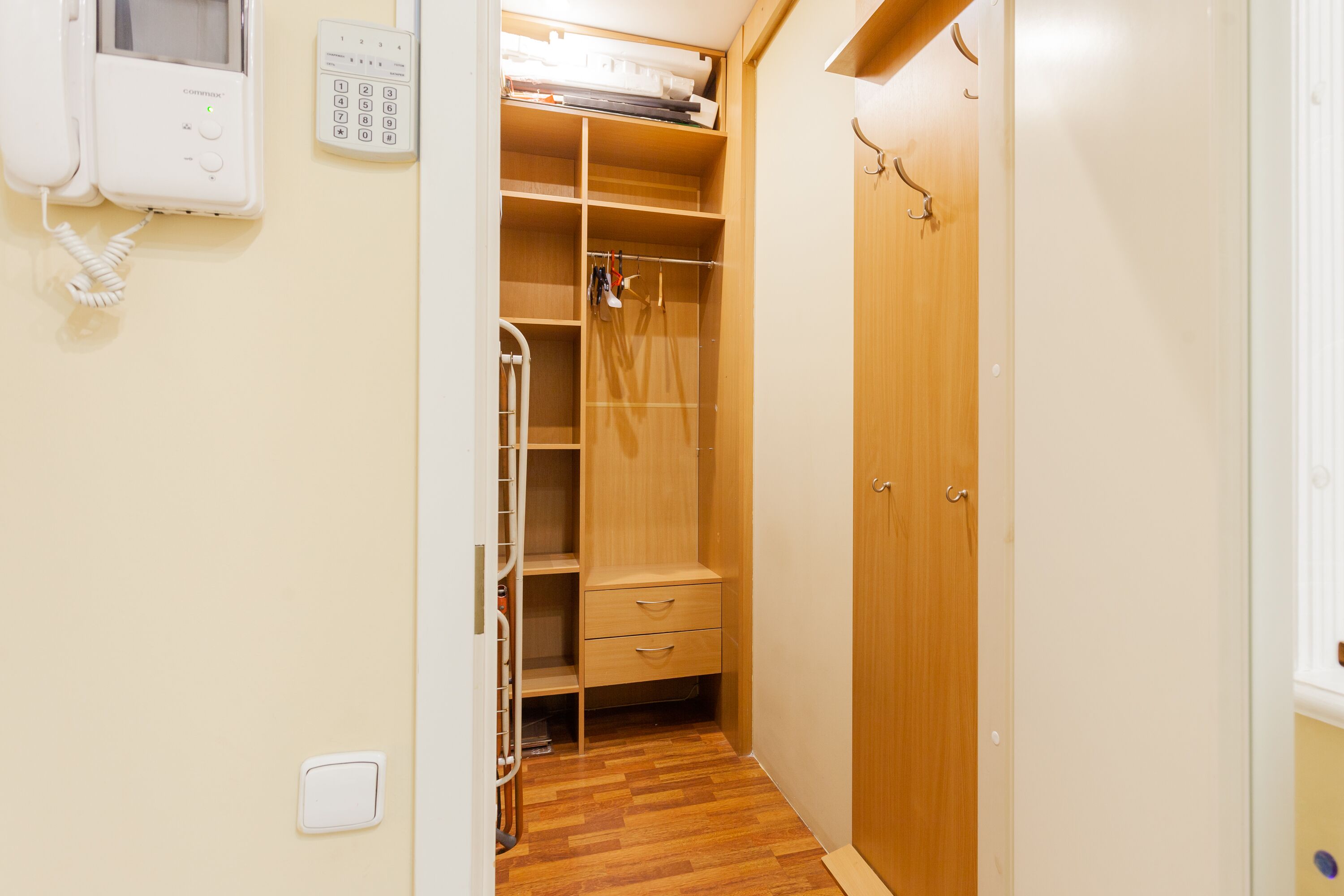 Un dressing avec des portes en bois, un téléphone intégré et une étagère avec des vêtements pliés.