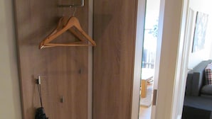 Una habitación moderna con un banco de madera, un perchero y una puerta que da a otra zona.