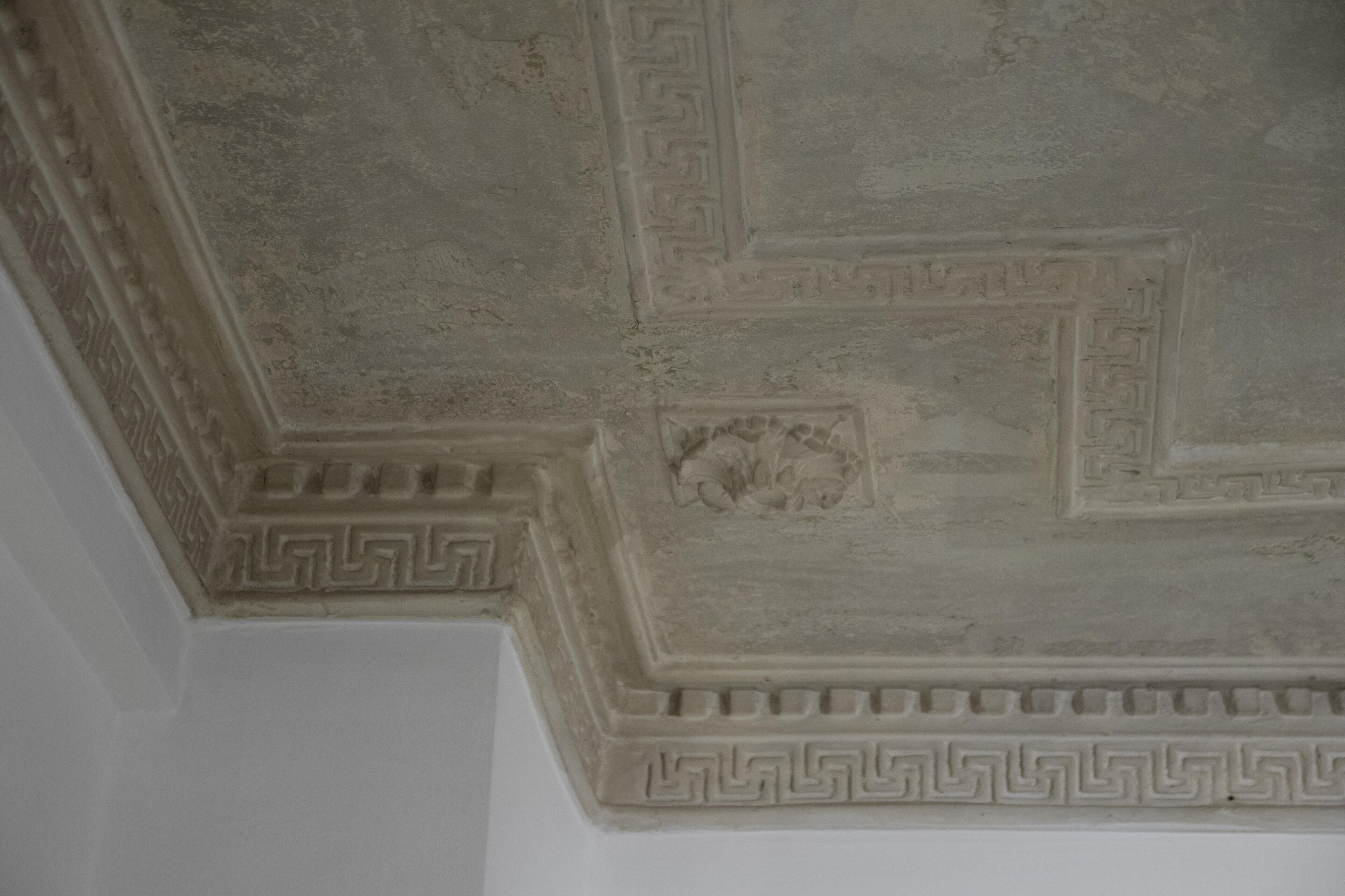 A ceiling with intricate geometric patterns and a central relief sculpture.