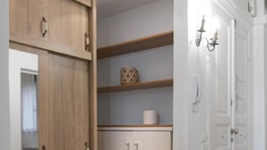A hallway with wooden flooring, a white wardrobe, and a white cabinet with shelves. - MAISON SALONIQUE 1930 (Thessaloniki)