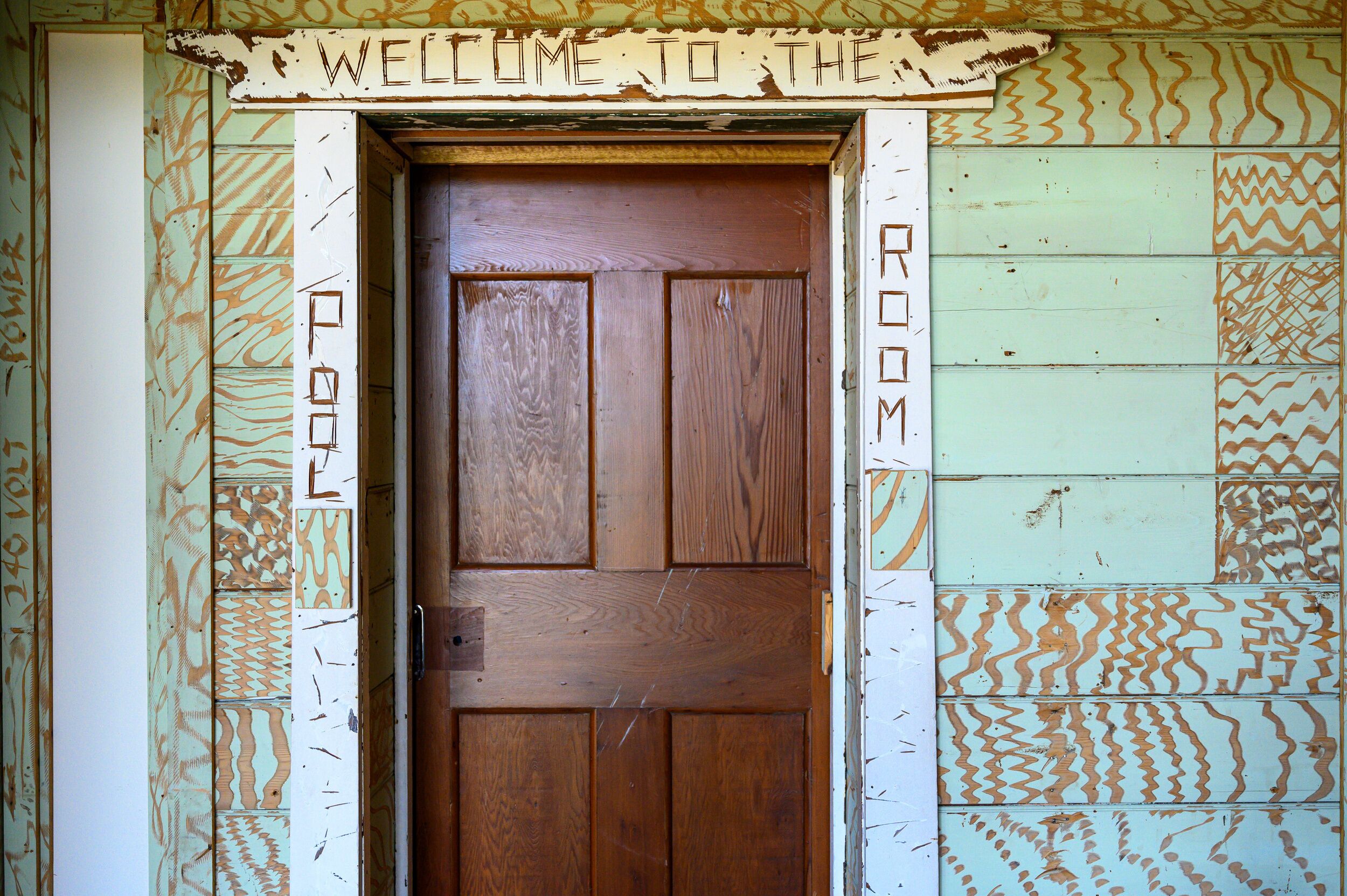 Une porte en bois avec une pancarte indiquant « BIENVENUE DANS CETTE CHAMBRE ».