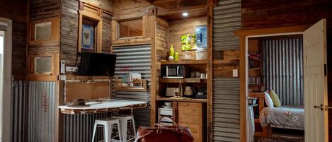 A cozy room with a bed, a desk, a chair, a television, and a bookshelf.