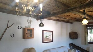 Una habitación rústica con vigas de madera a la vista, un armario de madera, un cuadro enmarcado, una lámpara y una cama con almohadas.