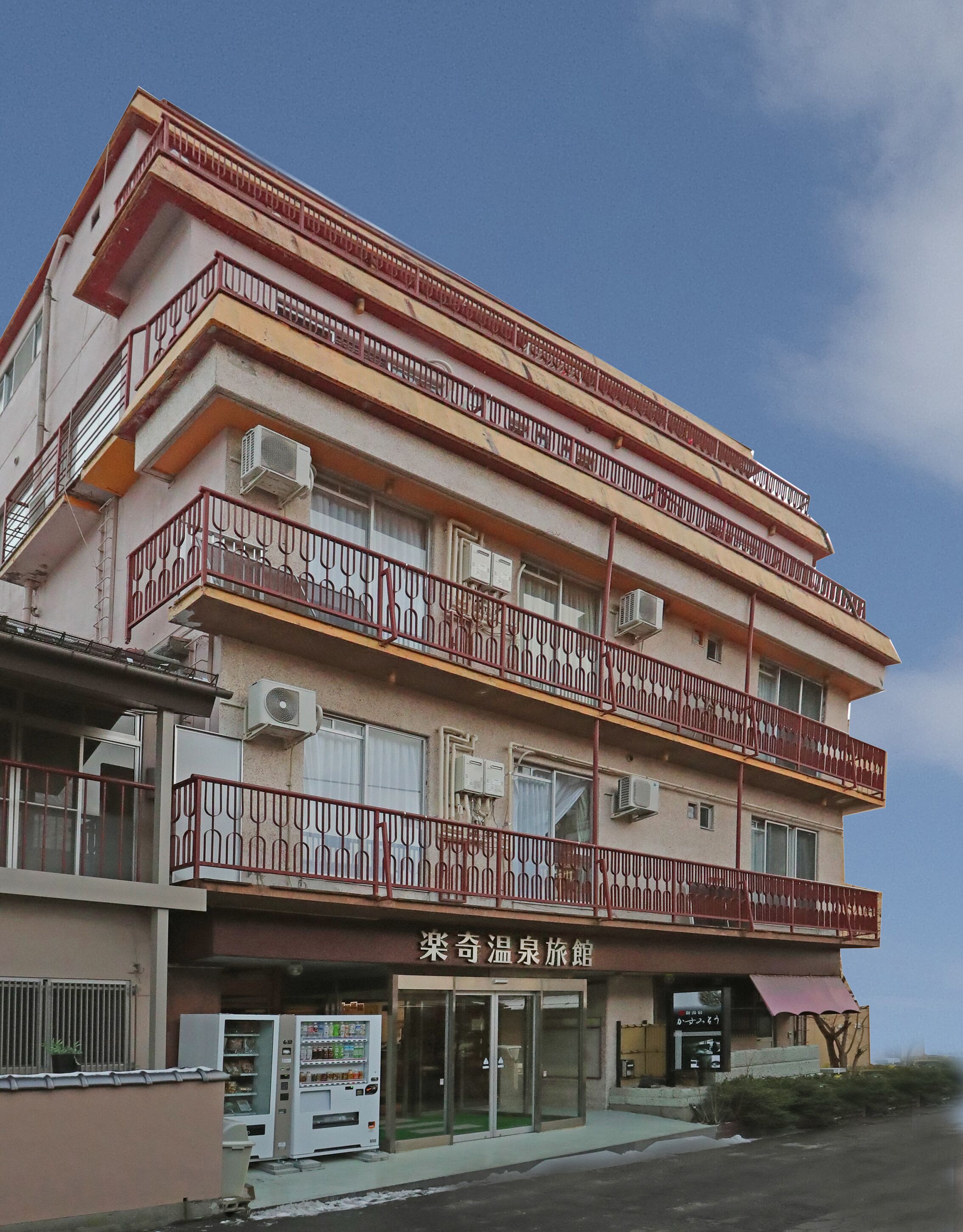 A multi-story building with balconies, air conditioning units, and a vending machine outside.