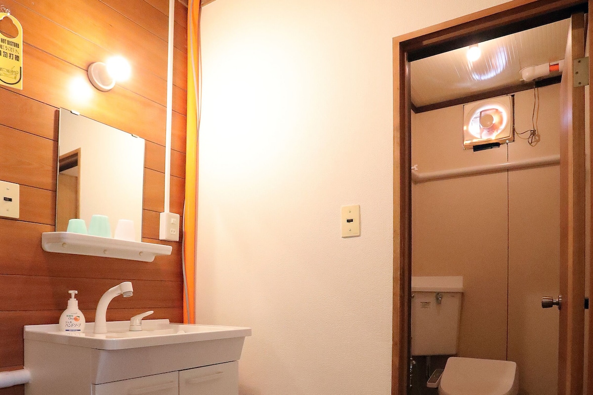 A bathroom with a sink, mirror, and toilet. There is a small rug on the floor.