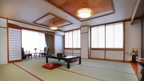A traditional Japanese room with tatami flooring, a low table, and sliding doors. - Raki Onsenryokan (Yamanouchi)