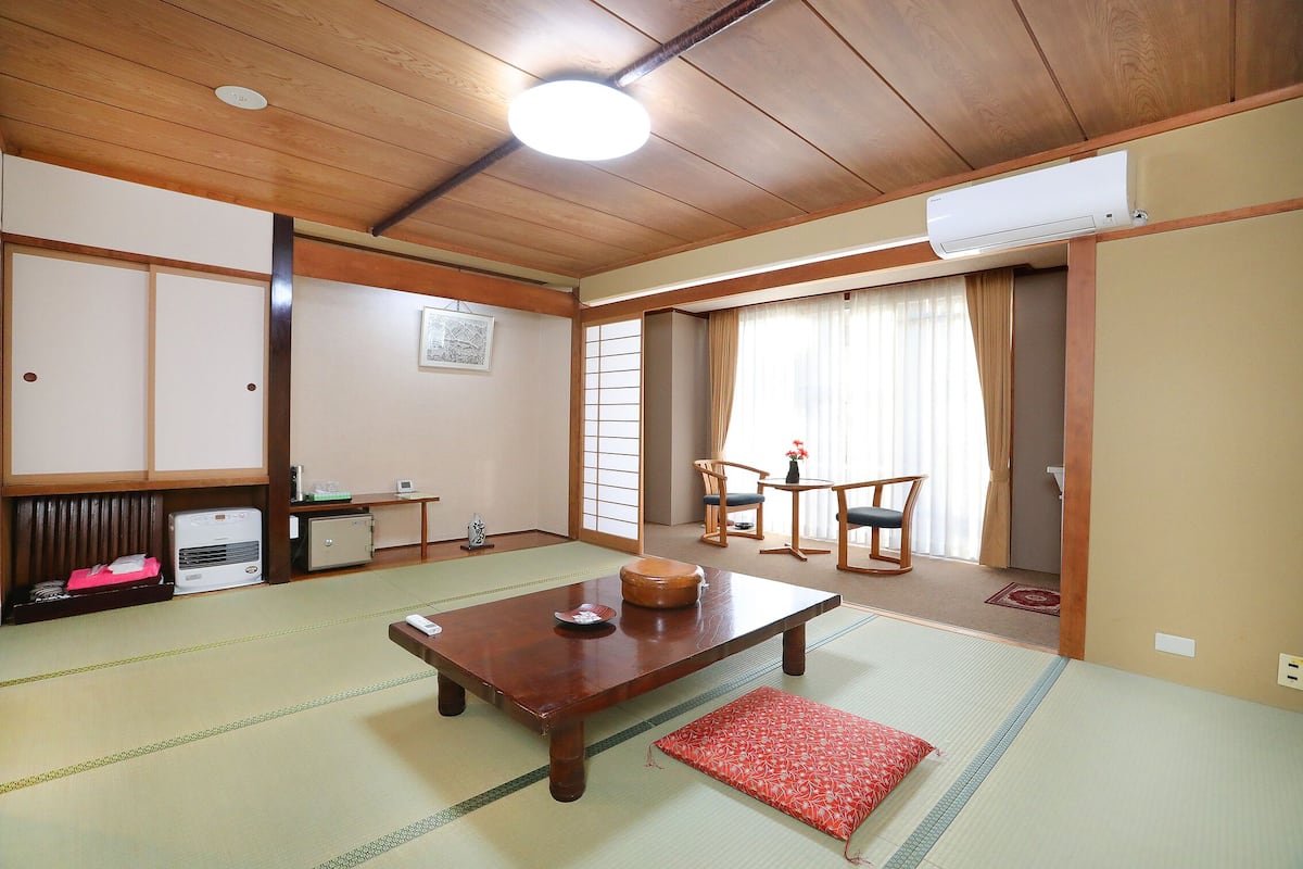 A traditional Japanese room with tatami flooring, a wooden table, a futon bed, and sliding doors.