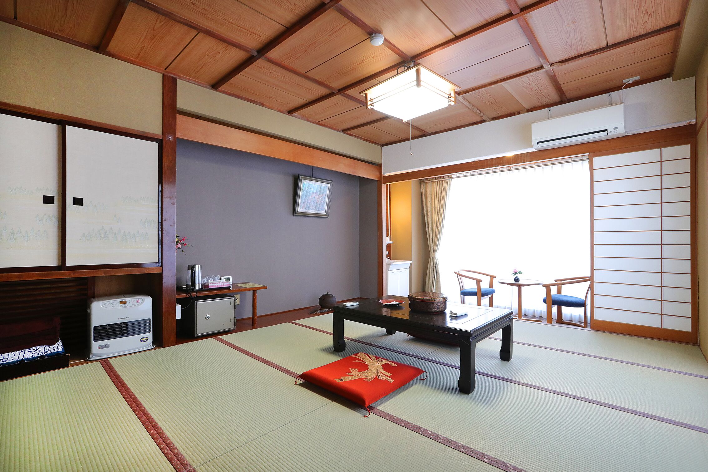 A traditional Japanese room with tatami flooring, a low table, a sofa, and sliding doors.
