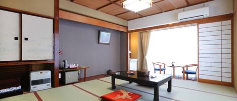 A traditional Japanese room with tatami flooring, a low table, a sofa, and sliding doors.
