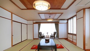 A traditional Japanese room with tatami flooring, a low table with a decorative item, and sliding doors. - Raki Onsenryokan (Yamanouchi)