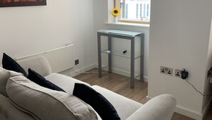 A modern room with a white sofa, a glass table, and a window with a view of buildings. - StayHere 3 (Leeds)