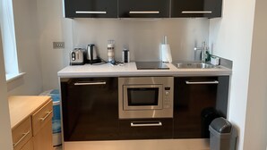 A modern kitchen with black cabinets, a stainless steel oven, a toaster, a kettle, and a sink. - StayHere 3 (Leeds)