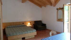 Een slaapkamer met houten plafond, een bed, een stoel, een tafel en een spiegel.