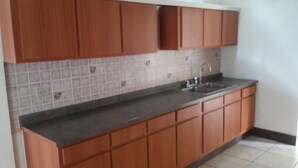 Eine Küche mit Holzausstattung, einer gefliesten Spritzschutzwand und einem Edelstahl-Spülbecken.