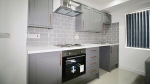 A modern kitchen with grey cabinets, a white countertop, and a built-in oven.