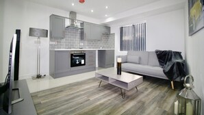 A modern living room with a grey sofa, a coffee table, and a TV stand.