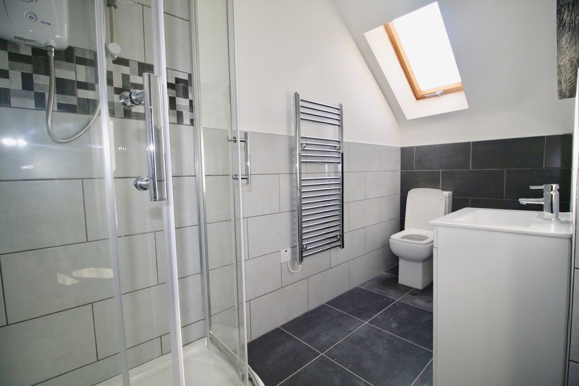 A modern bathroom with a glass-enclosed shower, a toilet, and a sink.