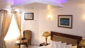 Ein Hotelzimmer mit einem Bett, einem Sessel, einem kleinen Tisch und einem Bild an der Wand.