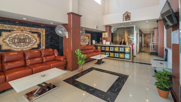 A spacious lobby with a leather sofa, a reception desk, and a large decorative wall. - Regenta Central Residency (Pattaya)