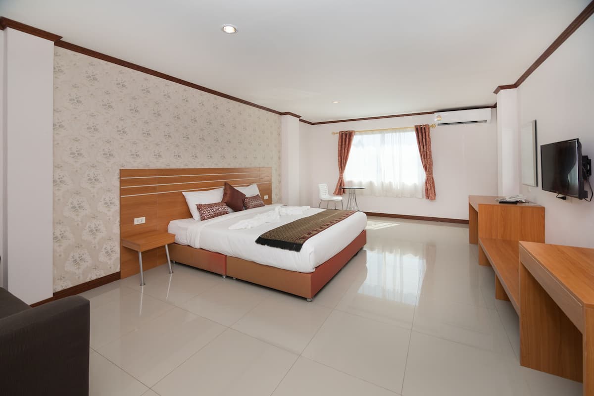 Quarto de hotel moderno com uma cama grande, uma escrivaninha e uma televisão.