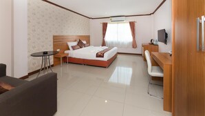 A hotel room with a bed, a desk, a chair, a small table, and a TV. - Regenta Central Residency (Pattaya)