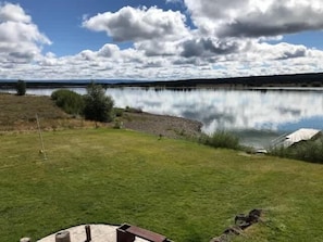 A lakeside view with a grassy area, a wooden deck, and a tent.