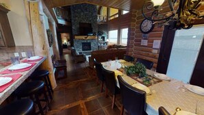 A cozy restaurant with a stone fireplace, wooden walls, and a dining area with tables set for four. - Waters Edge* 9Br+loft, 5.5Ba, Boat Dock, Wifi (Island Park)