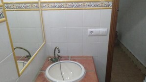 Ein Badezimmer mit weißem Waschbecken, einem Spiegel und einer gefliesten Rückwand.