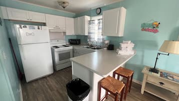 Een koelkast, een magnetron, kookgerei, borden en bestek