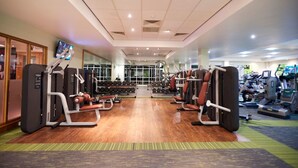 A gym with cardio machines, weightlifting equipment, and a TV screen on the wall. - The Lodge at Meyrick Park (Bournemouth)