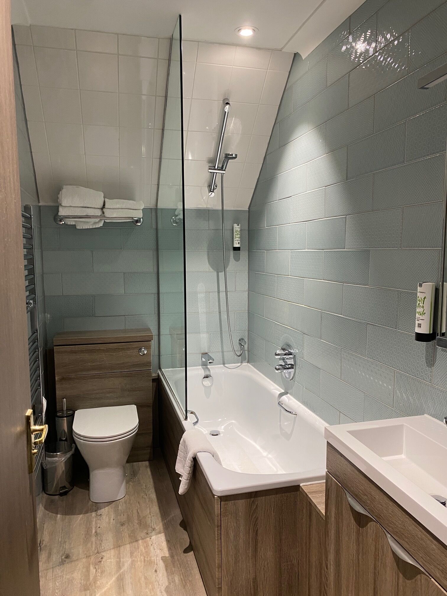 A modern bathroom with a glass-enclosed shower, a wooden vanity, and a separate sink.