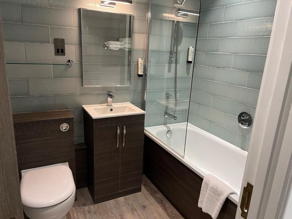 A modern bathroom with a toilet, vanity, and a glass-enclosed shower area.