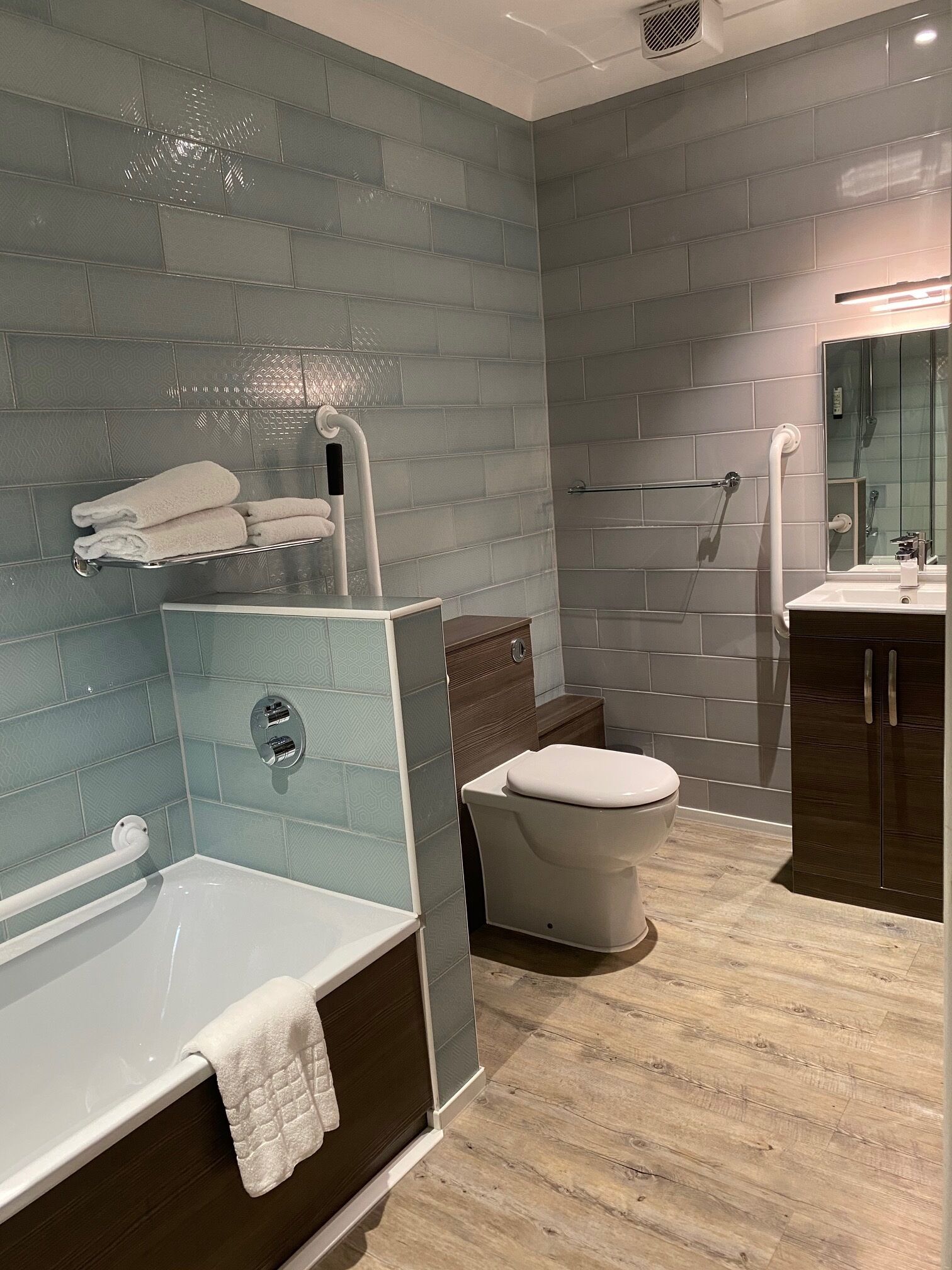 A modern bathroom with a bathtub, toilet, and shower.