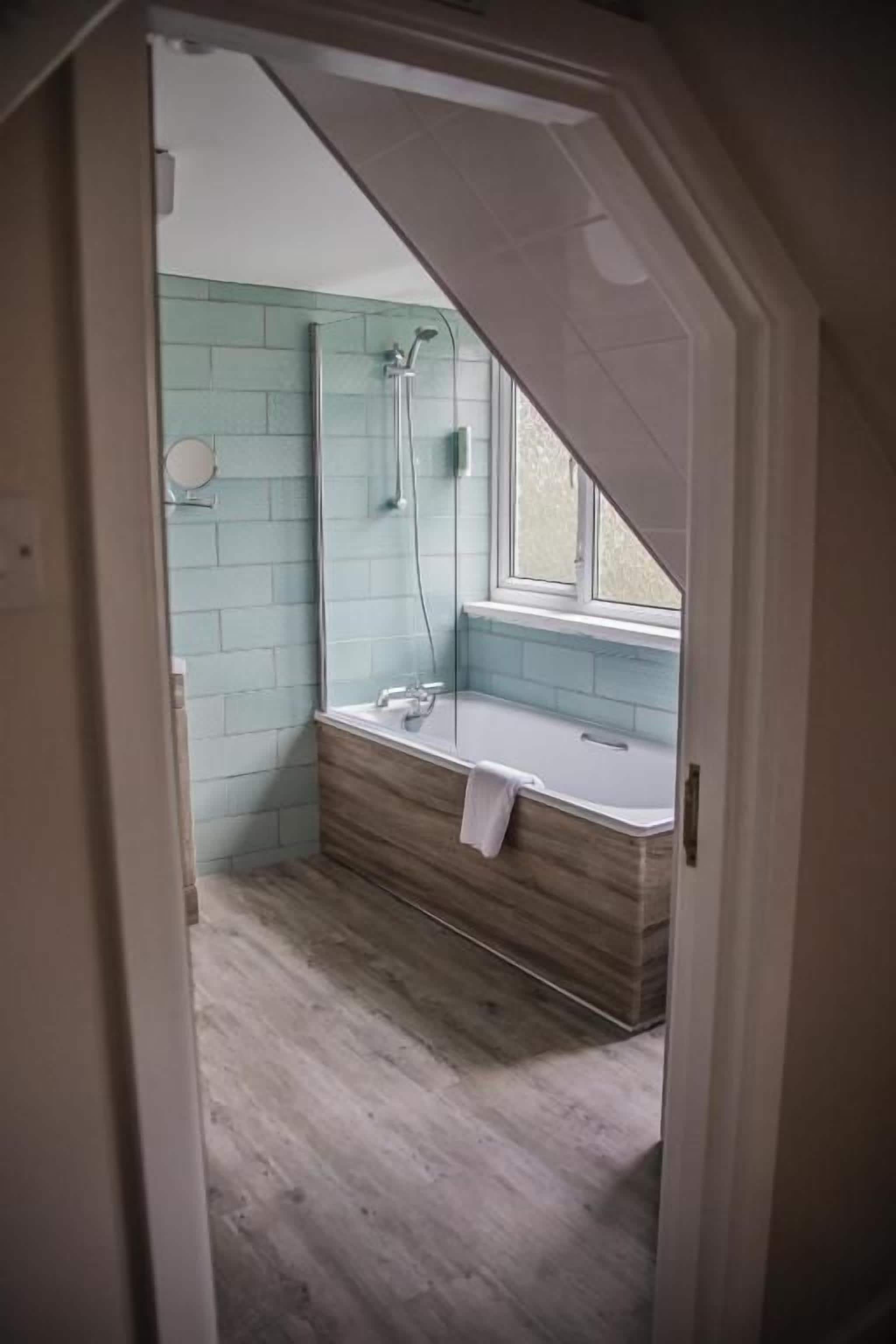 A bathroom with a shower, a bathtub, and a window.