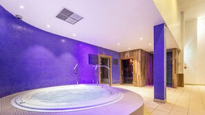 A modern indoor swimming pool with a circular design, surrounded by a purple-tiled wall and wooden accents. - The Lodge at Meyrick Park (Bournemouth)