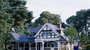 A traditional Tudor-style building with a steeply pitched roof, multiple windows, and a porch with white railings. - The Lodge at Meyrick Park (Bournemouth)