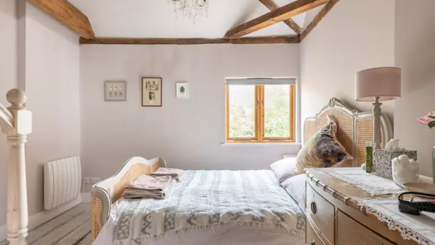 Ein Schlafzimmer mit Bett, Schminktisch, Fenster und einer Chandelier.