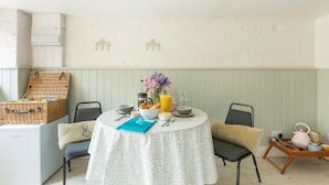 Ein Essbereich mit einem runden Tisch, gedeckt für ein Frühstück, inklusive Korb, Blumen und einer Kanne Orangensaft.