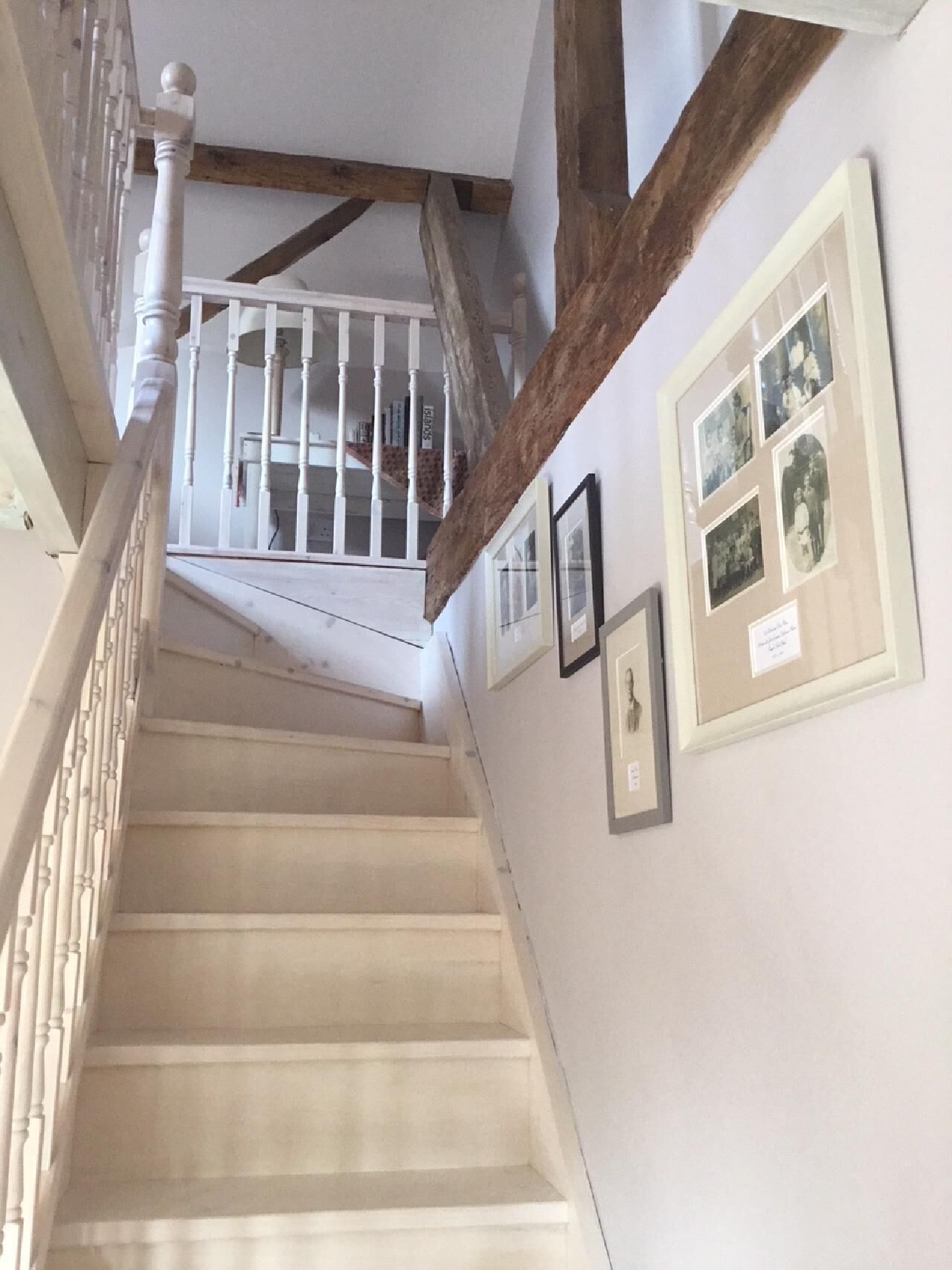 Una escalera con balaustres blancos y estructura de vigas de madera.