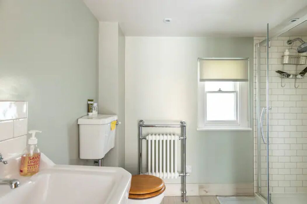 A modern bathroom with a bathtub, toilet, and glass shower enclosure.