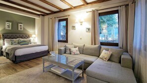 A bedroom with a bed, a sofa, a glass coffee table, and a window with curtains. - Almond House Suites Arachova - Adults Only (Distomo-Arachova-Antikyra)