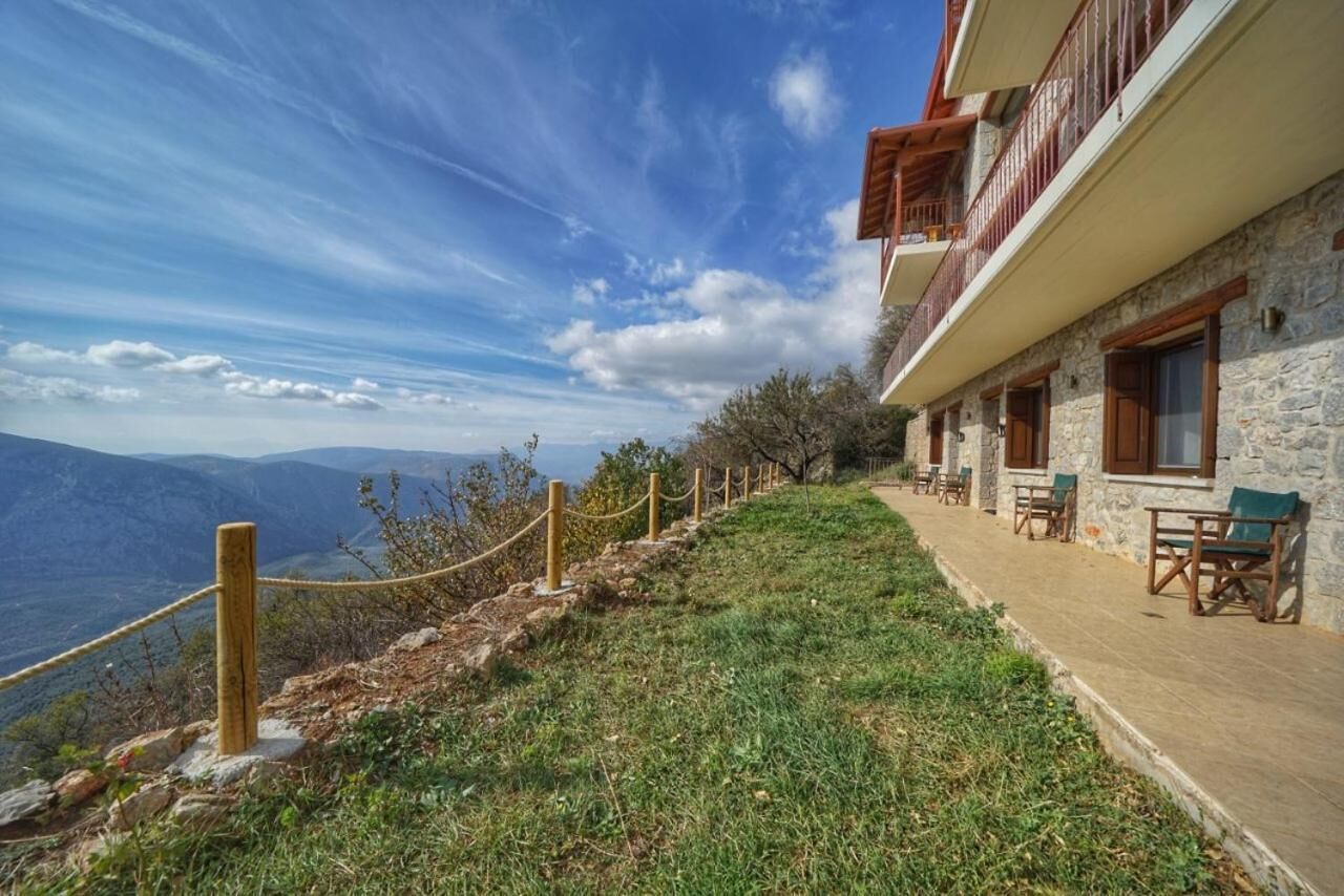 Un bâtiment en pierre doté d’un balcon, d’une barrière en corde et offrant une vue sur les montagnes.